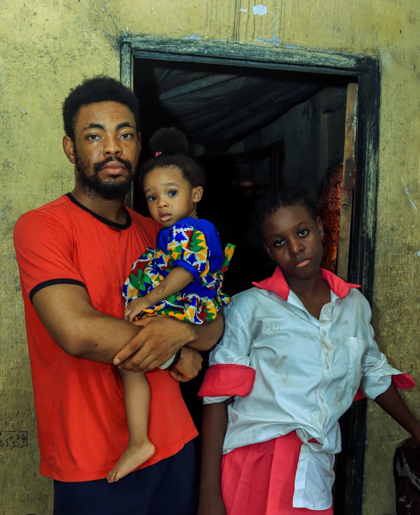 A father holds his daughter beside his sister at the doorway