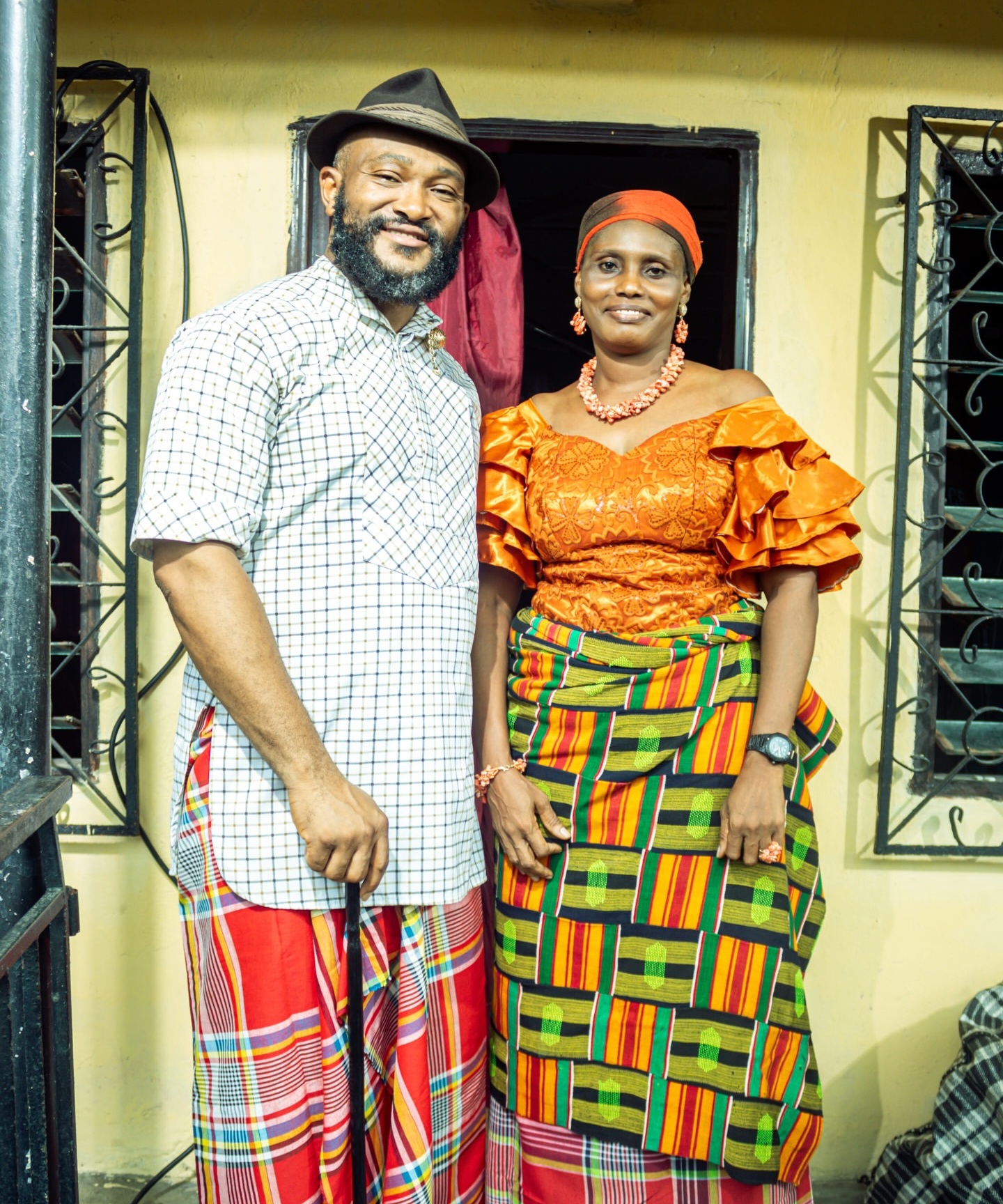 Parents in traditional attire outside the family home