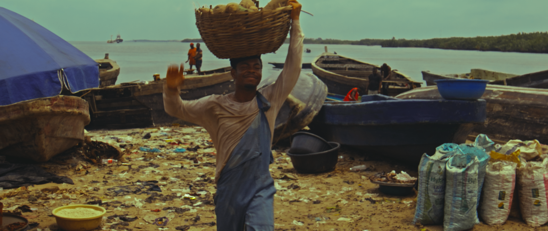 A young vendor carries his basket along the riverbank