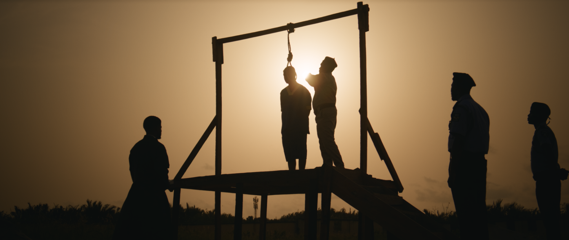 Silhouettes at the gallows against a sunset sky