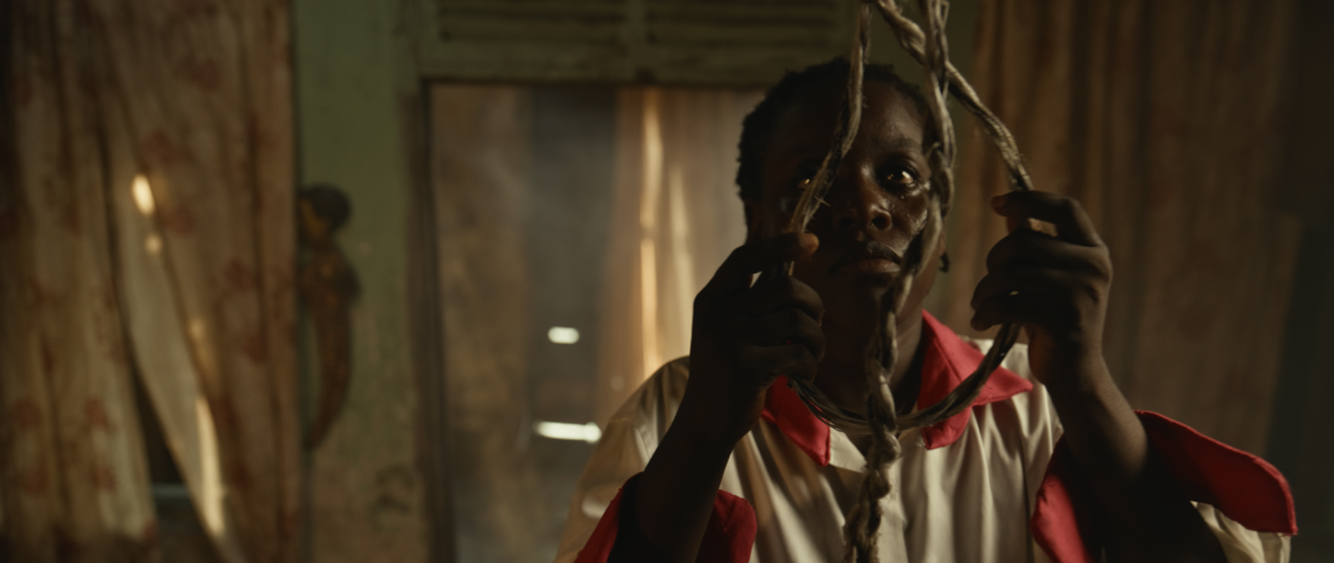 A young girl examines a length of rope in lamplight